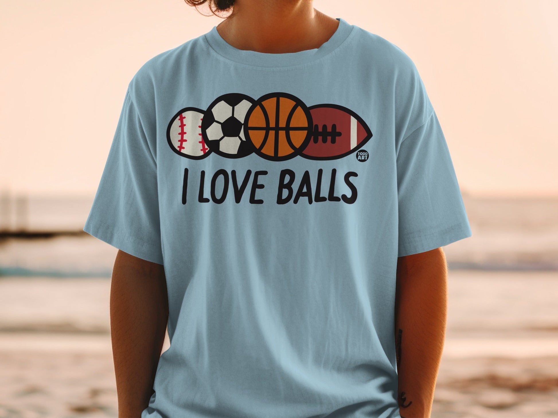 Light blue t-shirt with sports balls and "I LOVE BALLS" text.