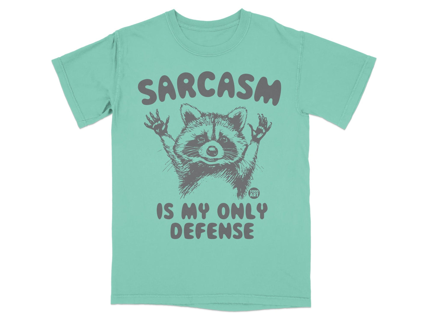 Green t-shirt with raccoon graphic and text "SARCAST IS MY ONLY DEFENSE".