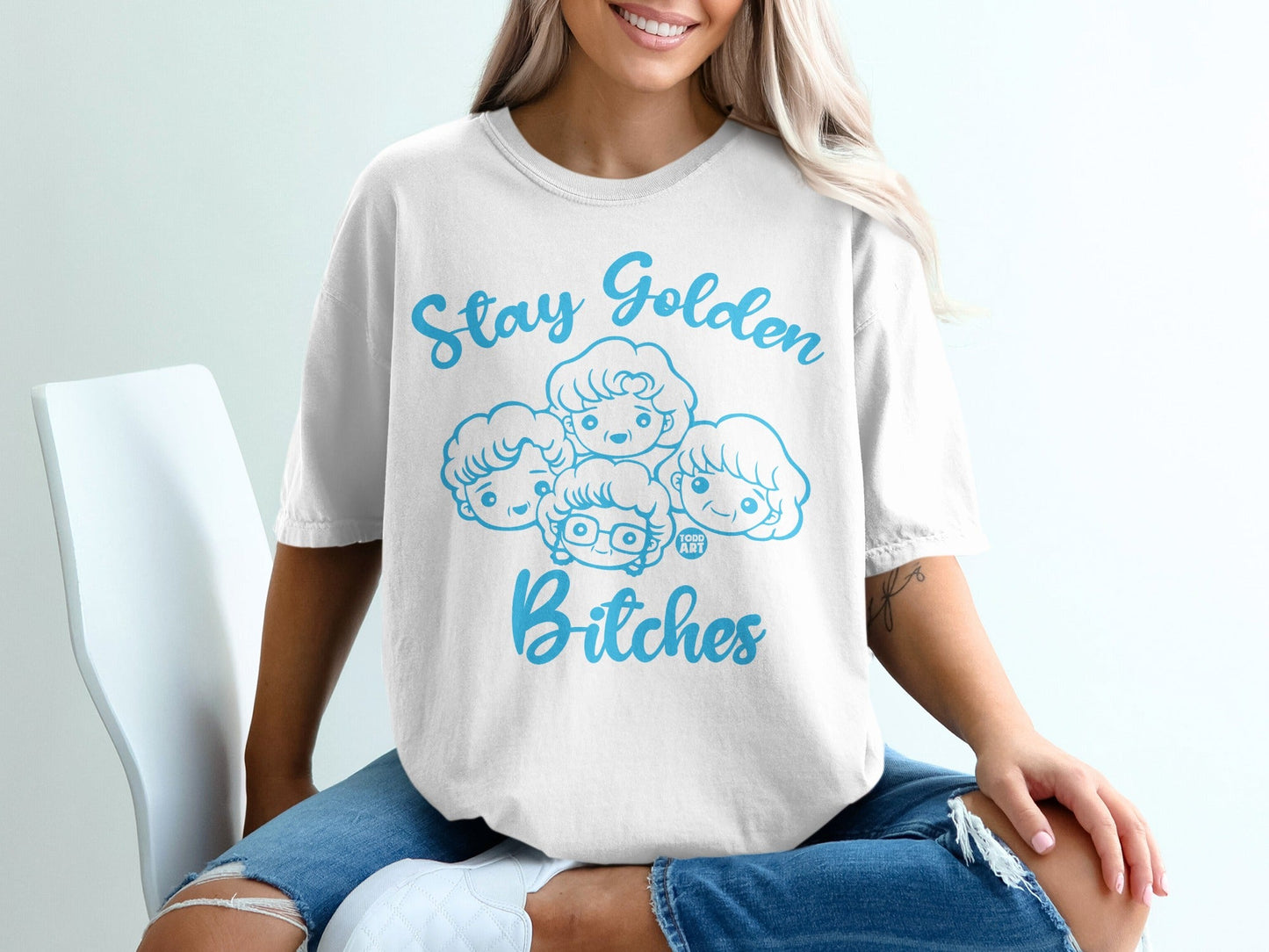 White t-shirt with blue cartoon faces and "Stay Golden Bitches" text.