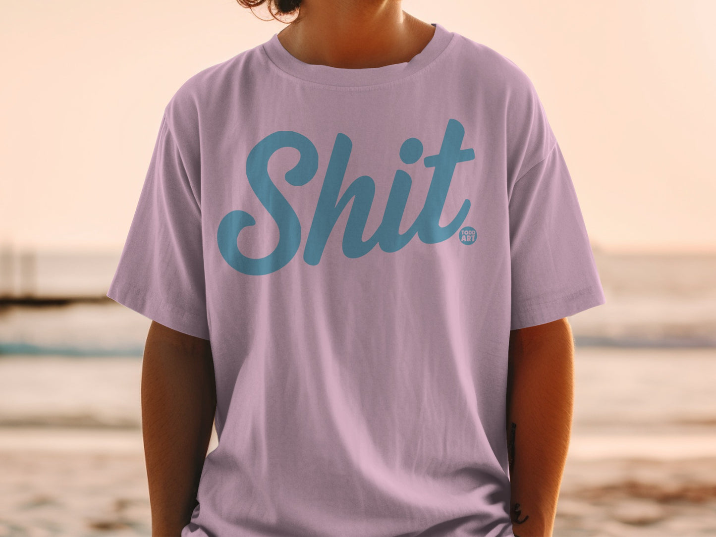 Lavender t-shirt with "Shit" in blue script and a small "LOGO ART" tag.