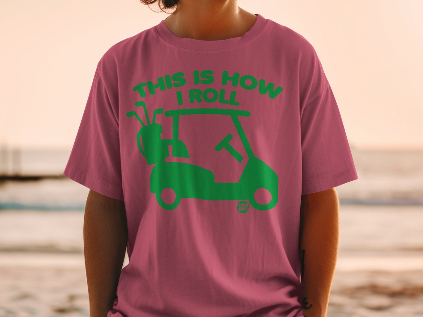 Pink t-shirt with green graphic of a golf cart and text "This Is How I Roll".