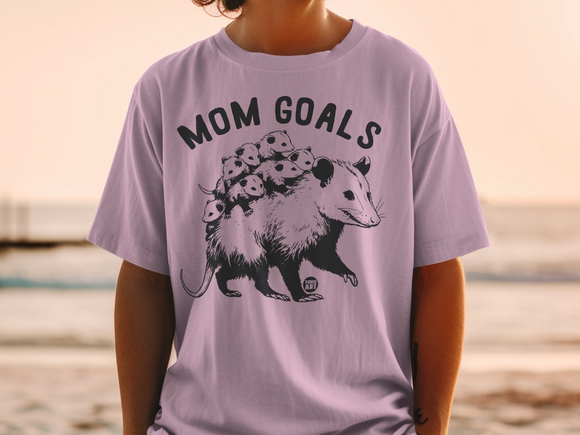Opossum carrying babies on its back with "Mom Goals" text.
