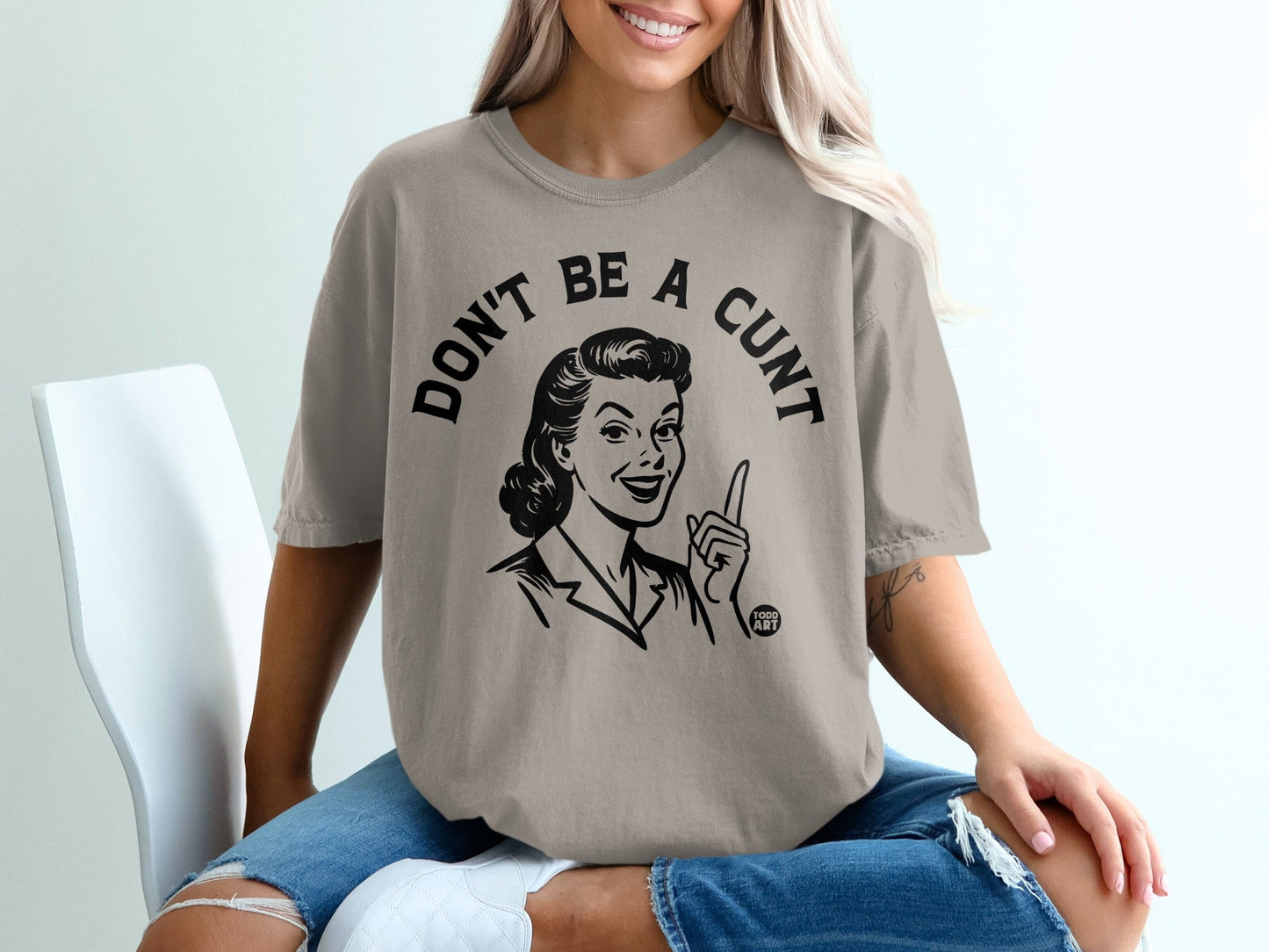 T-shirt with "DON'T BE A CUNT" text and a retro drawing of a woman pointing.