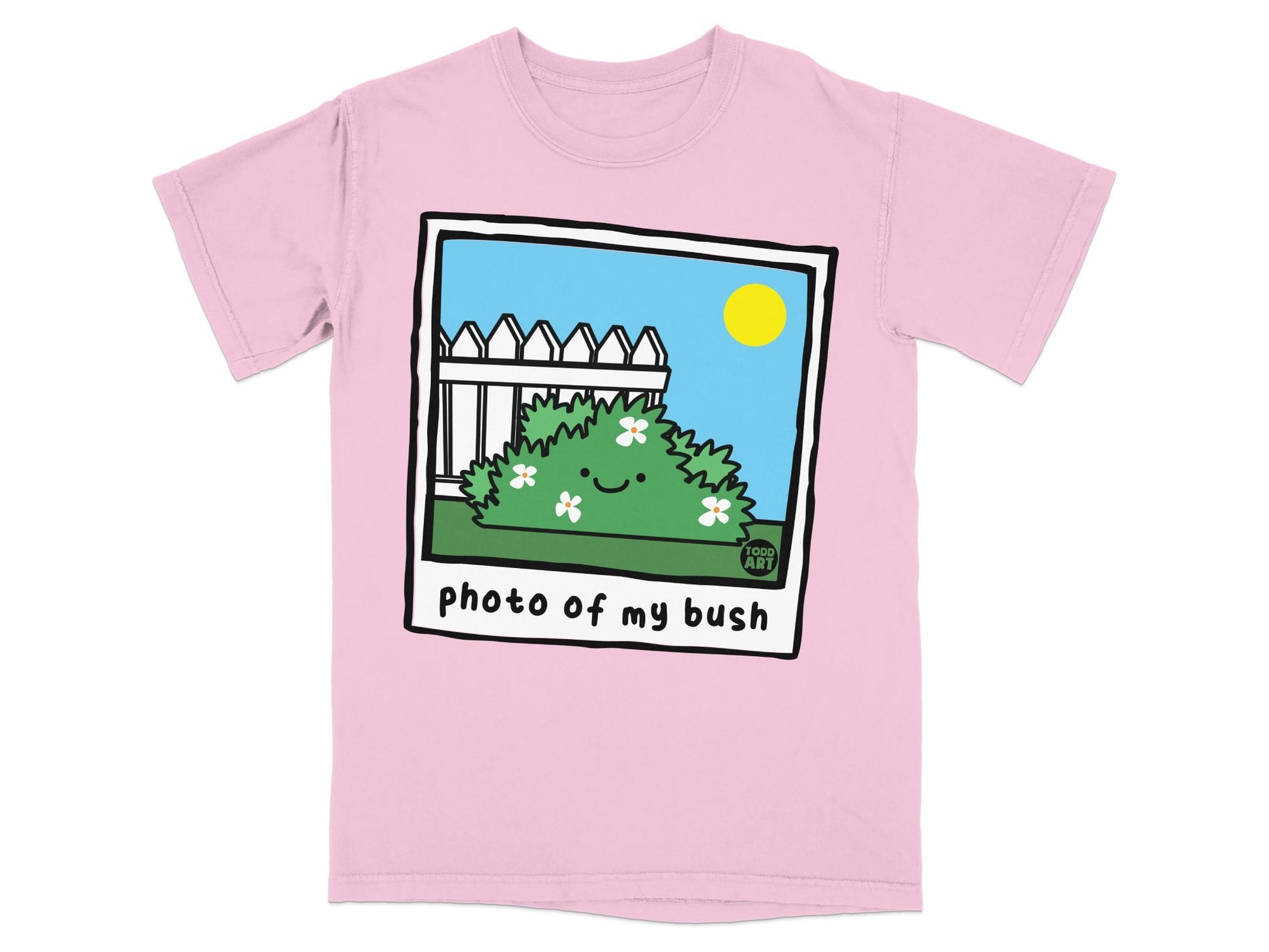 Pink t-shirt with a cartoon photo of a smiling bush with flowers and a white picket fence.