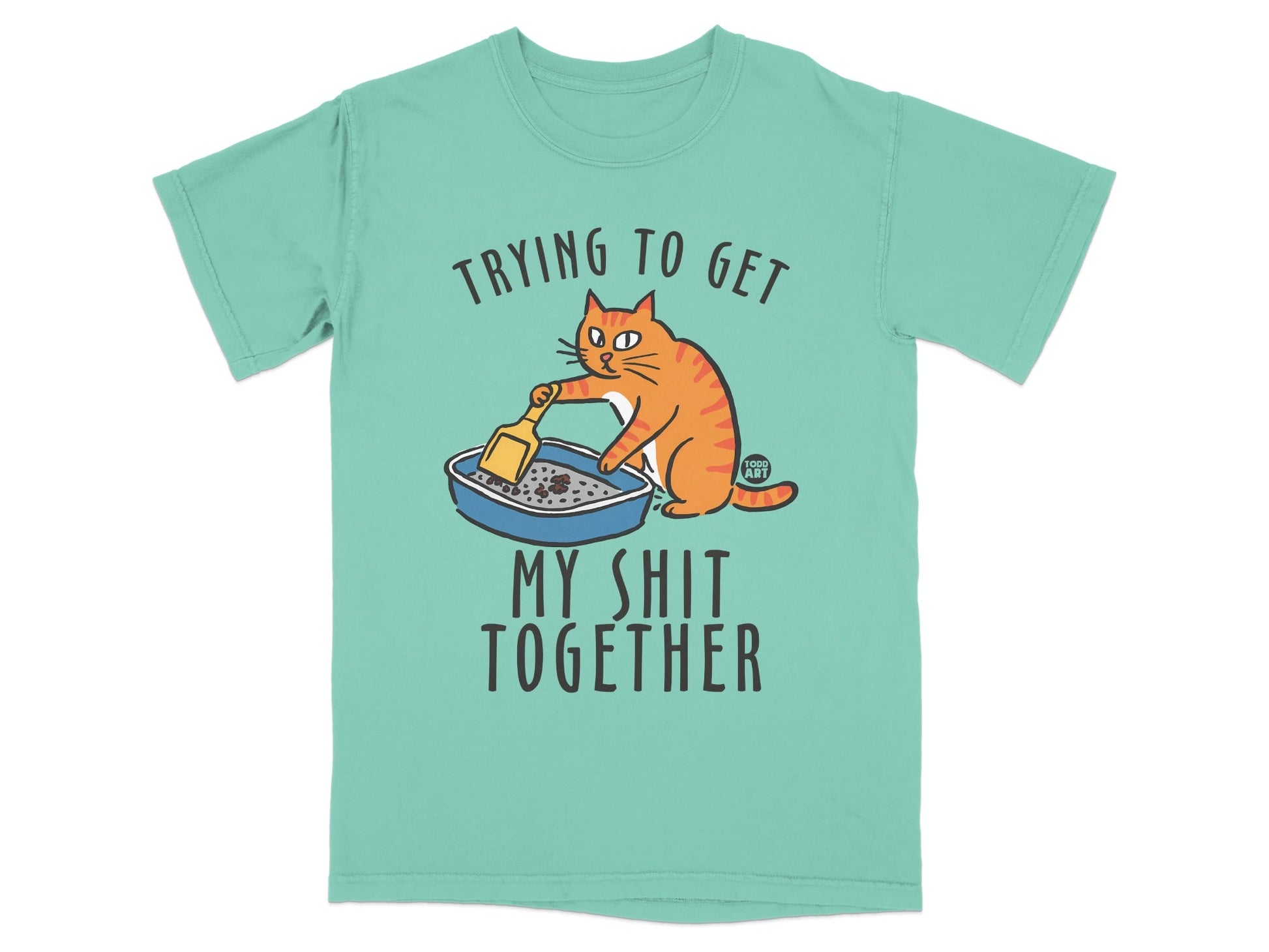 T-shirt with cartoon cat scooping litter box and text "Trying to get my shit together".