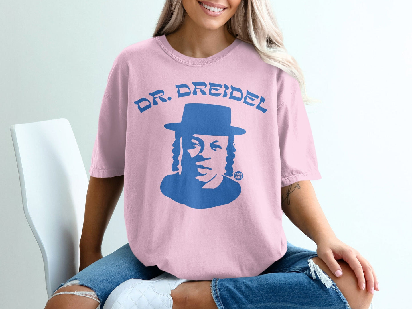 Pink t-shirt with blue "DR. DREIDEL" graphic and portrait.