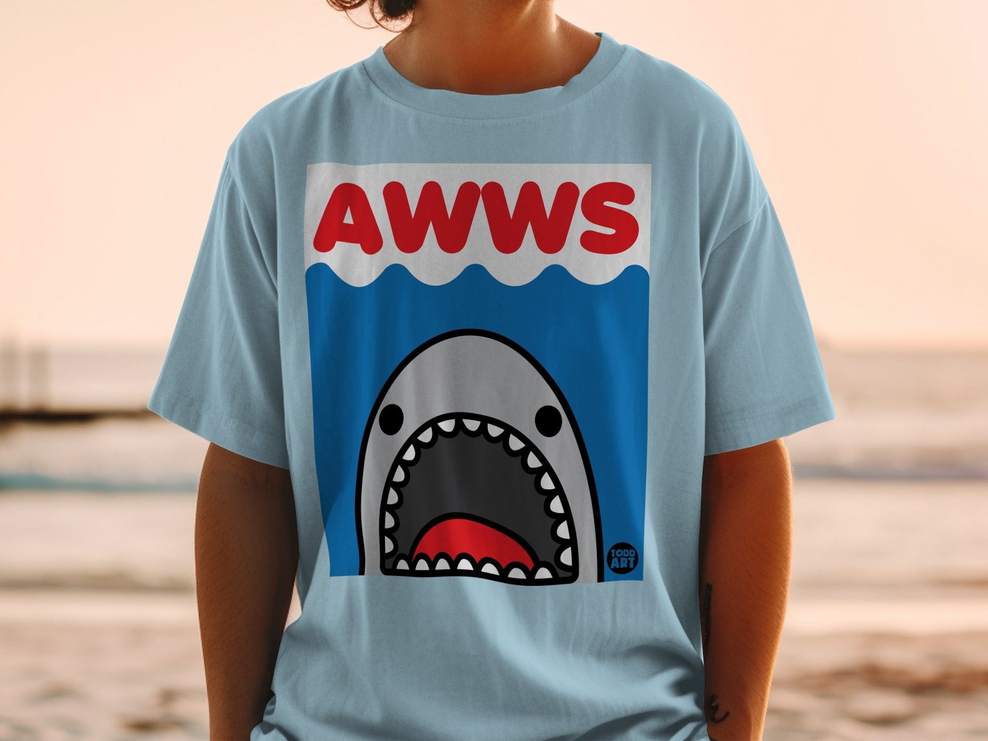 Light blue t-shirt with a cartoon shark graphic and "AWWS" text.