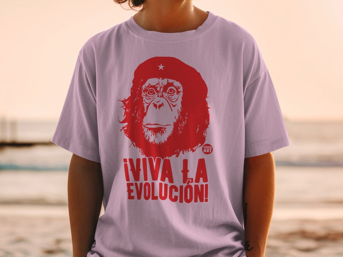 Red primate graphic with ¬°VIVA LA EVOLUCI√ìN! text on a light purple t-shirt.