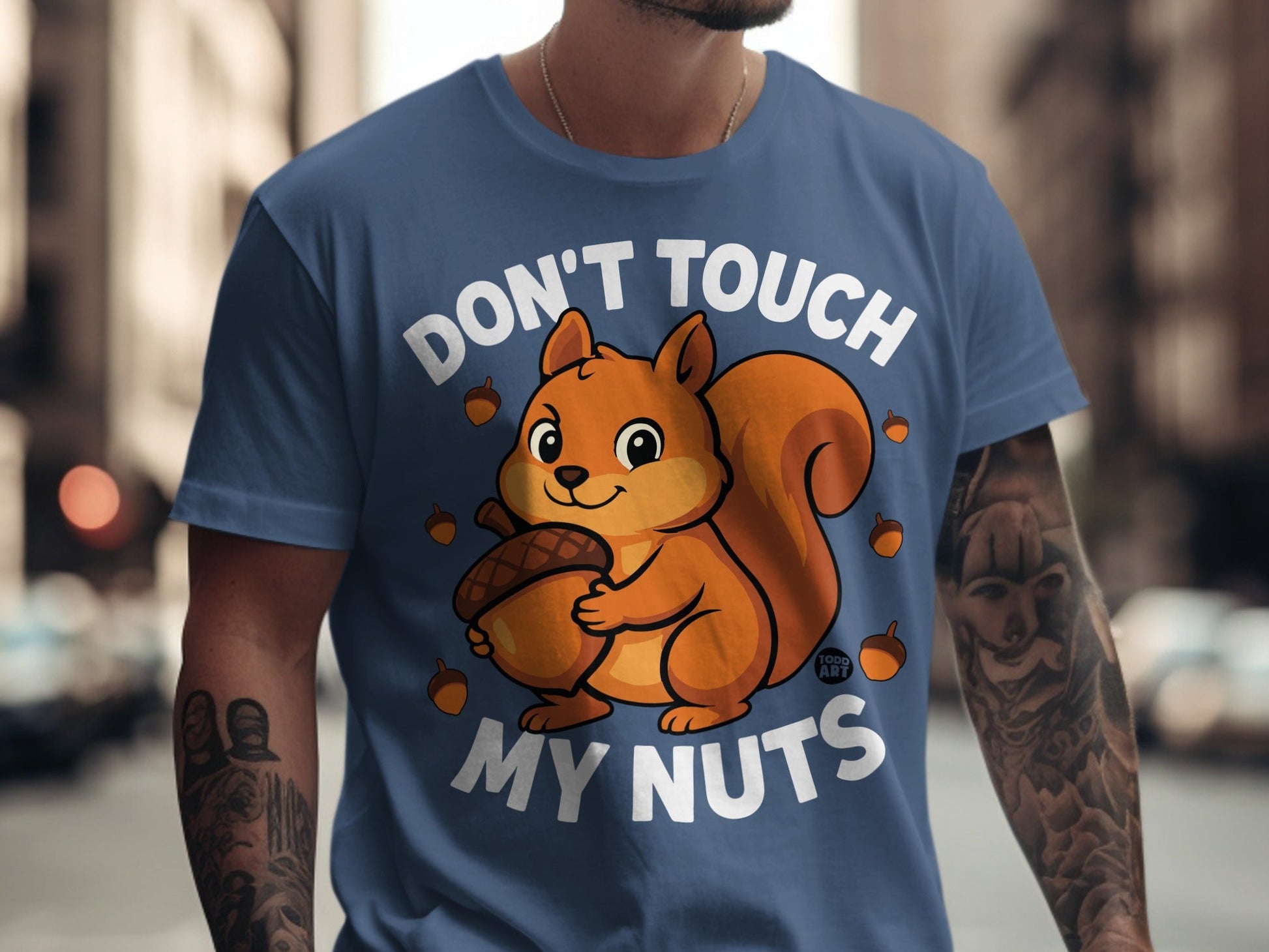 Blue t-shirt with a cartoon squirrel holding an acorn and the text "Don't Touch My Nuts".