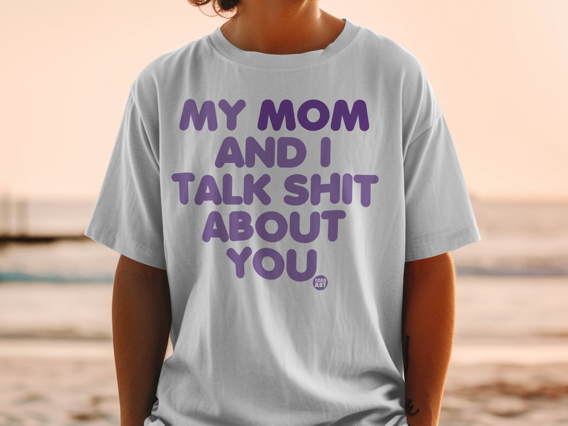 T-shirt with purple text "MY MOM AND I TALK SHIT ABOUT YOU" and "1000 ART".