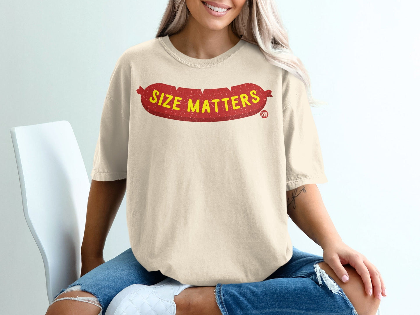 Cream t-shirt with red text "Size Matters" in a sausage shape.