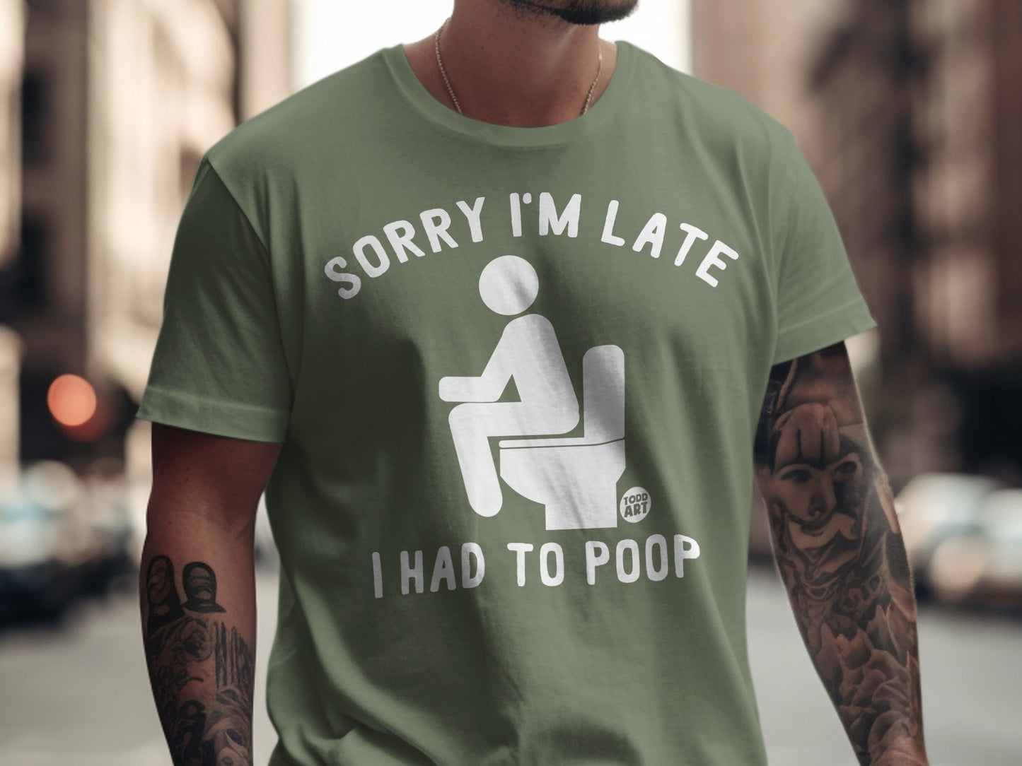Olive green t-shirt with white text and graphic: "SORRY I'M LATE I HAD TO POOP".