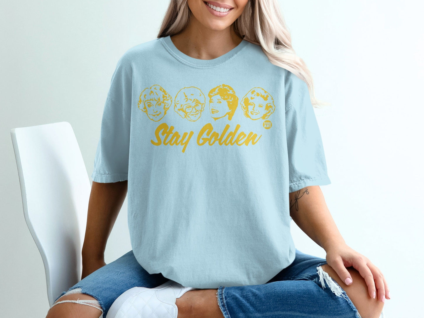Light blue t-shirt with four cartoon portraits and "Stay Golden" text.