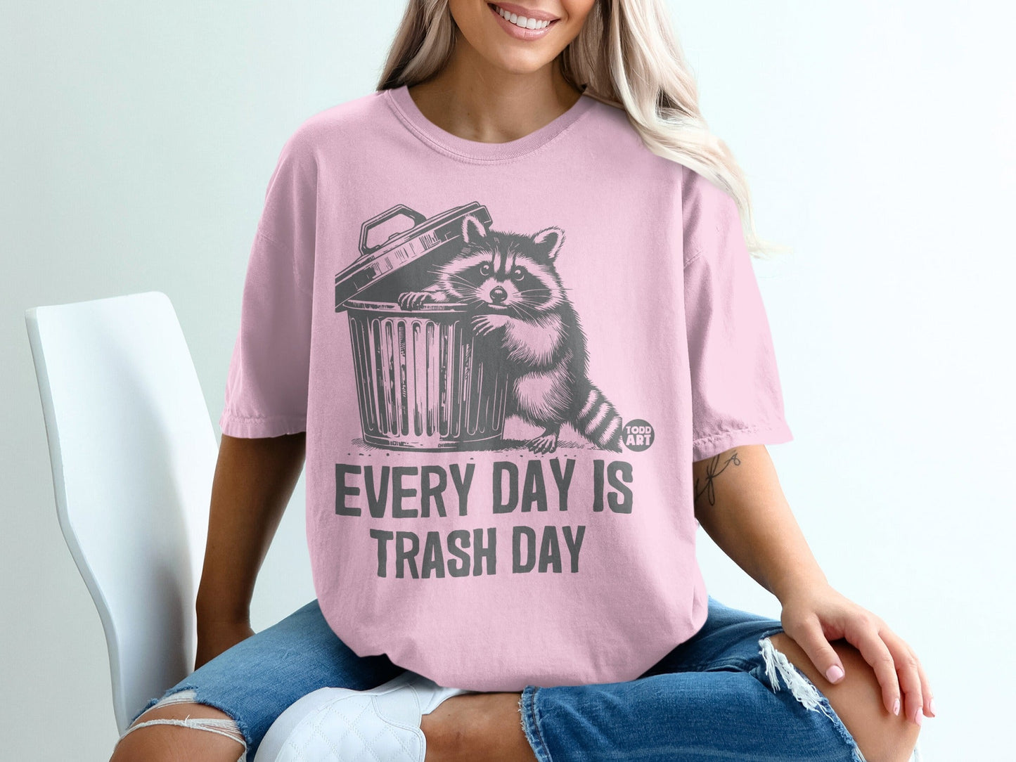 Pink t-shirt with raccoon emerging from trash can, "Every Day Is Trash Day" text.