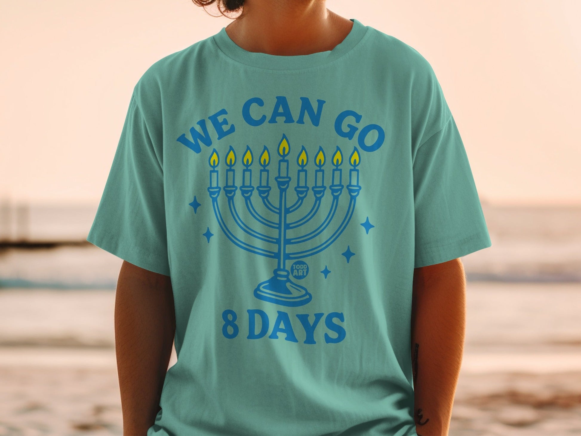 Teal t-shirt with "We Can Go 8 Days" and menorah graphic.
