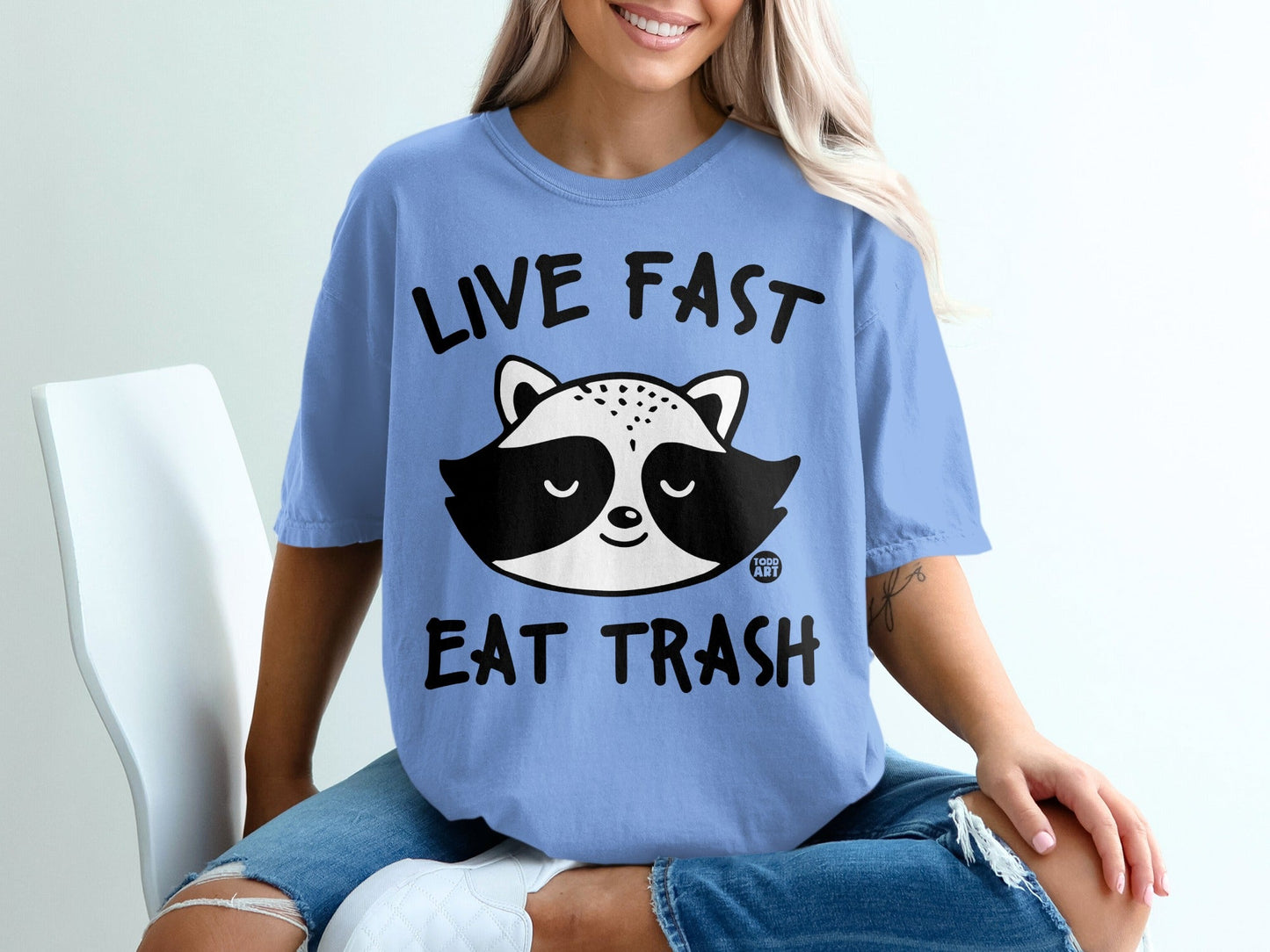 Blue t-shirt with a raccoon face and "LIVE FAST EAT TRASH" text.