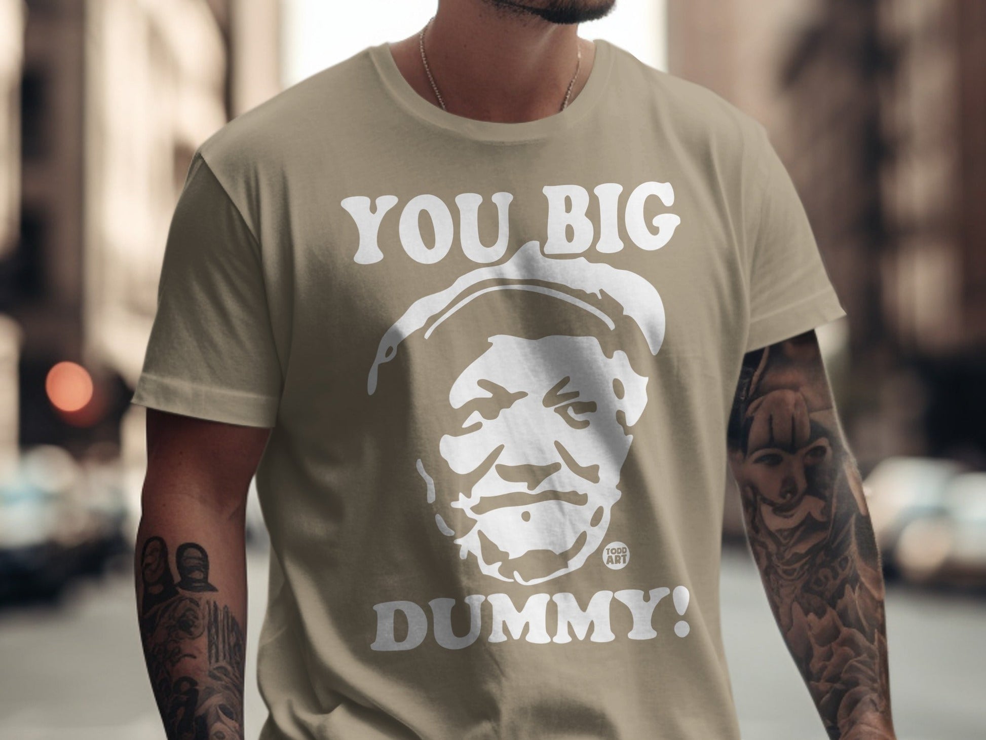 Tan t-shirt with white text "YOU BIG DUMMY!" and a portrait.