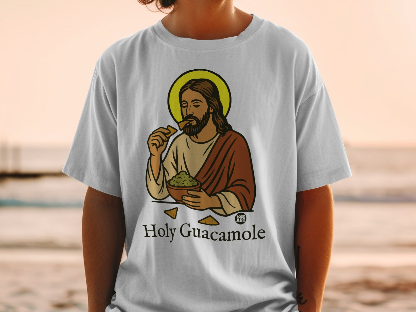 White t-shirt with Jesus eating guacamole and chips, text "Holy Guacamole".