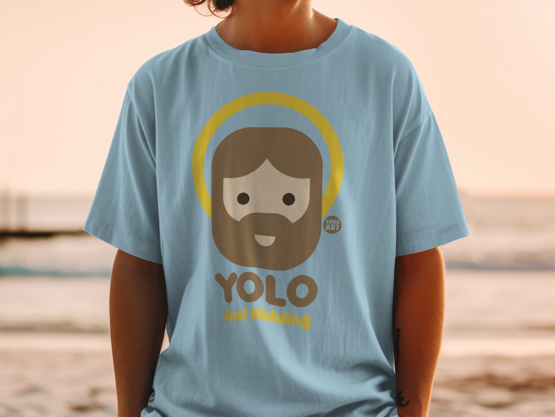 Light blue t-shirt with cartoon Jesus, "YOLO Just Kidding" text, and halo.