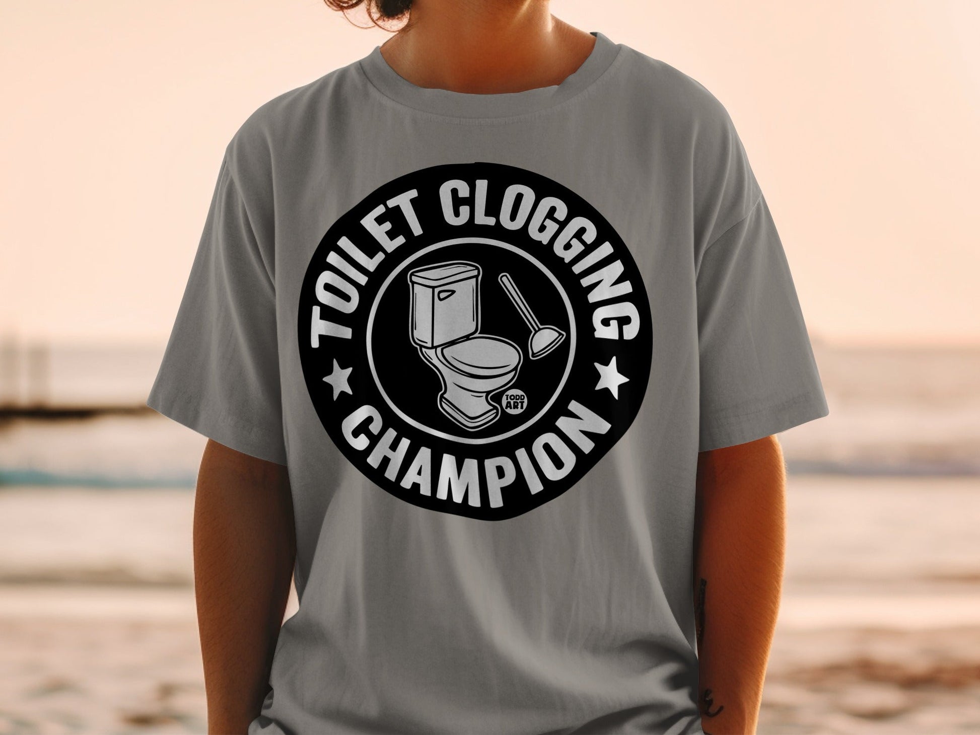 Gray t-shirt with "Toilet Clogging Champion" text and toilet brush graphic.
