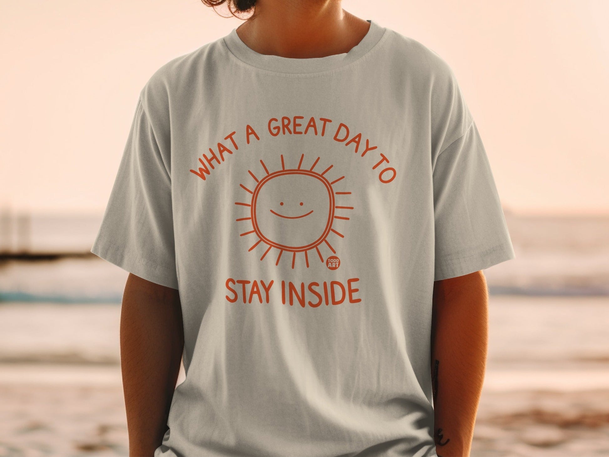 T-shirt with orange sun graphic and "What a great day to stay inside" text.