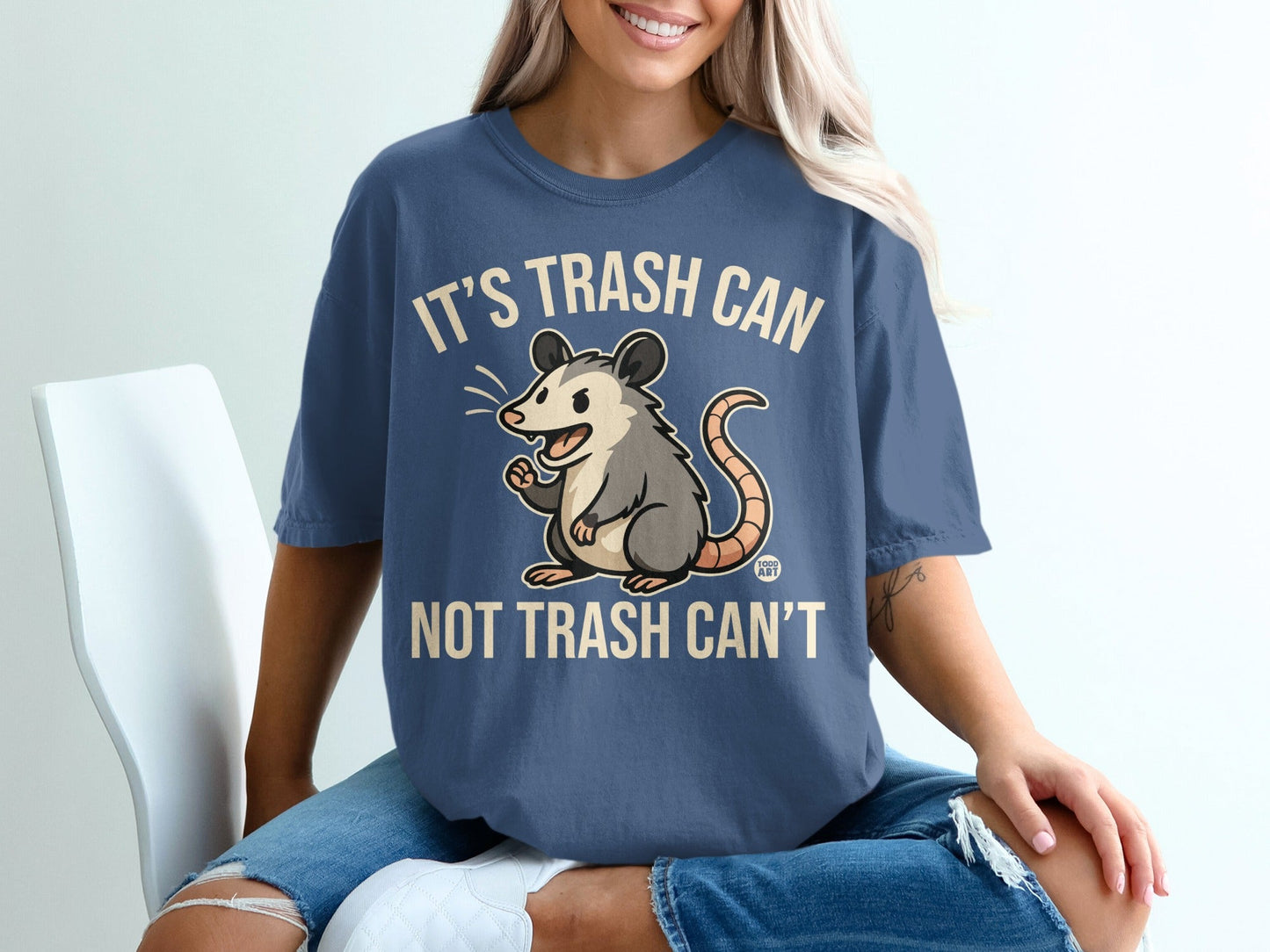 Blue t-shirt with a cartoon opossum and text "IT'S TRASH CAN NOT TRASH CAN'T".