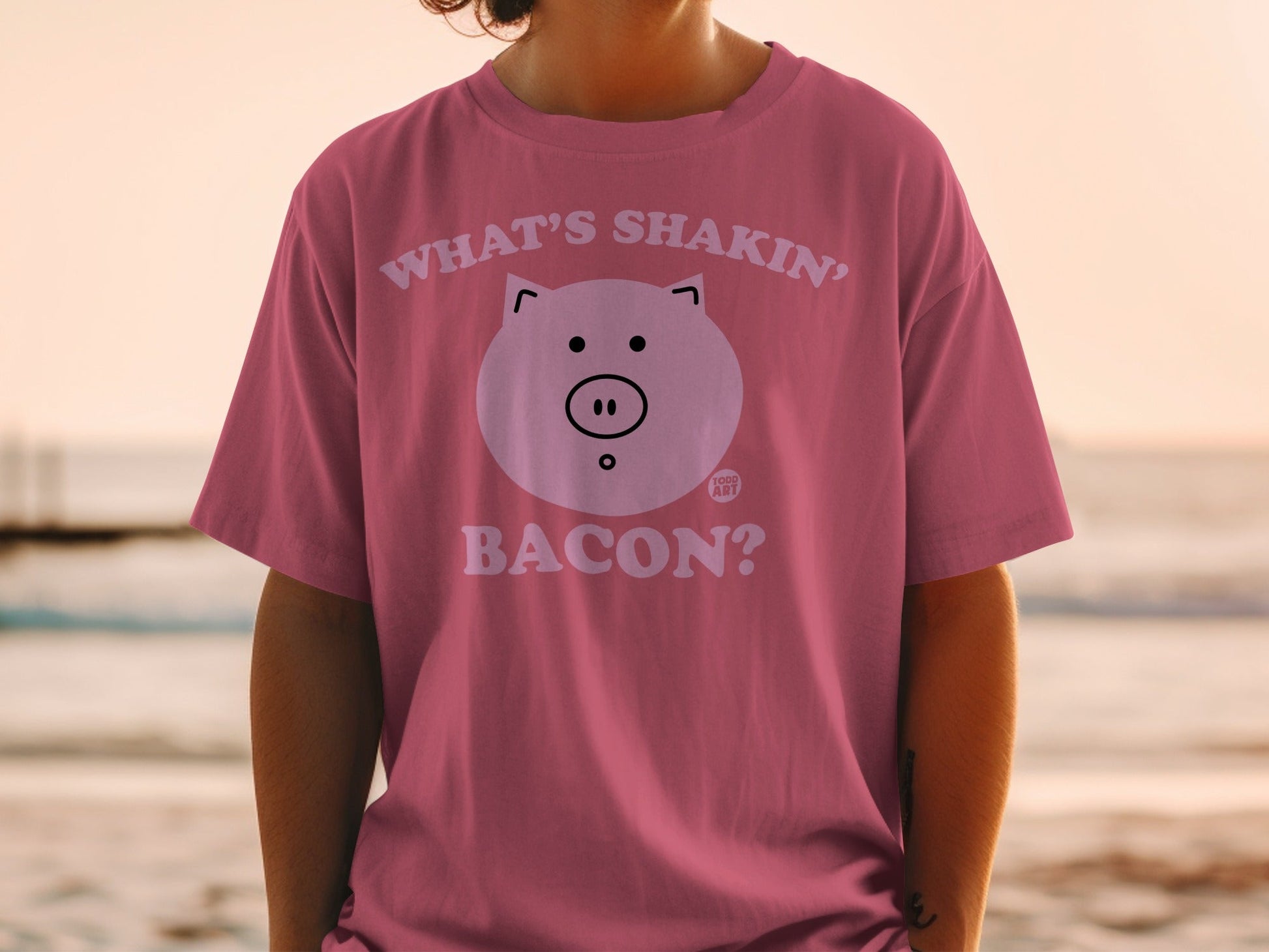 Pink t-shirt with "What's shakin' bacon?" text and a pig face graphic.