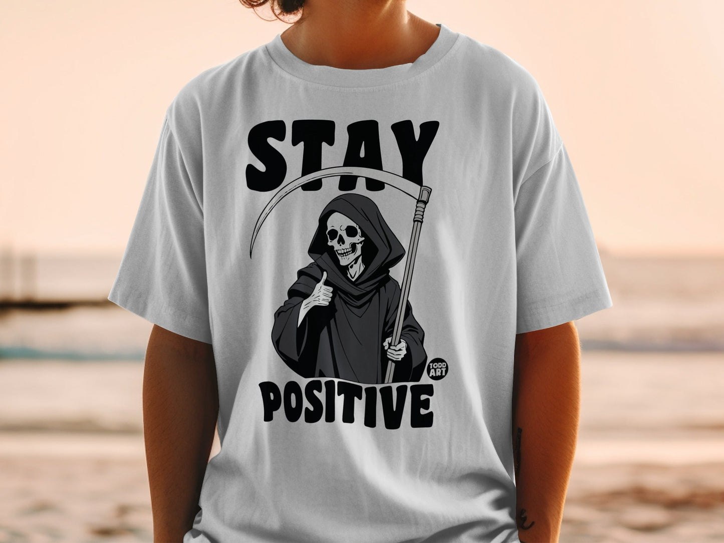 Grim Reaper graphic on t-shirt with "STAY POSITIVE" text.