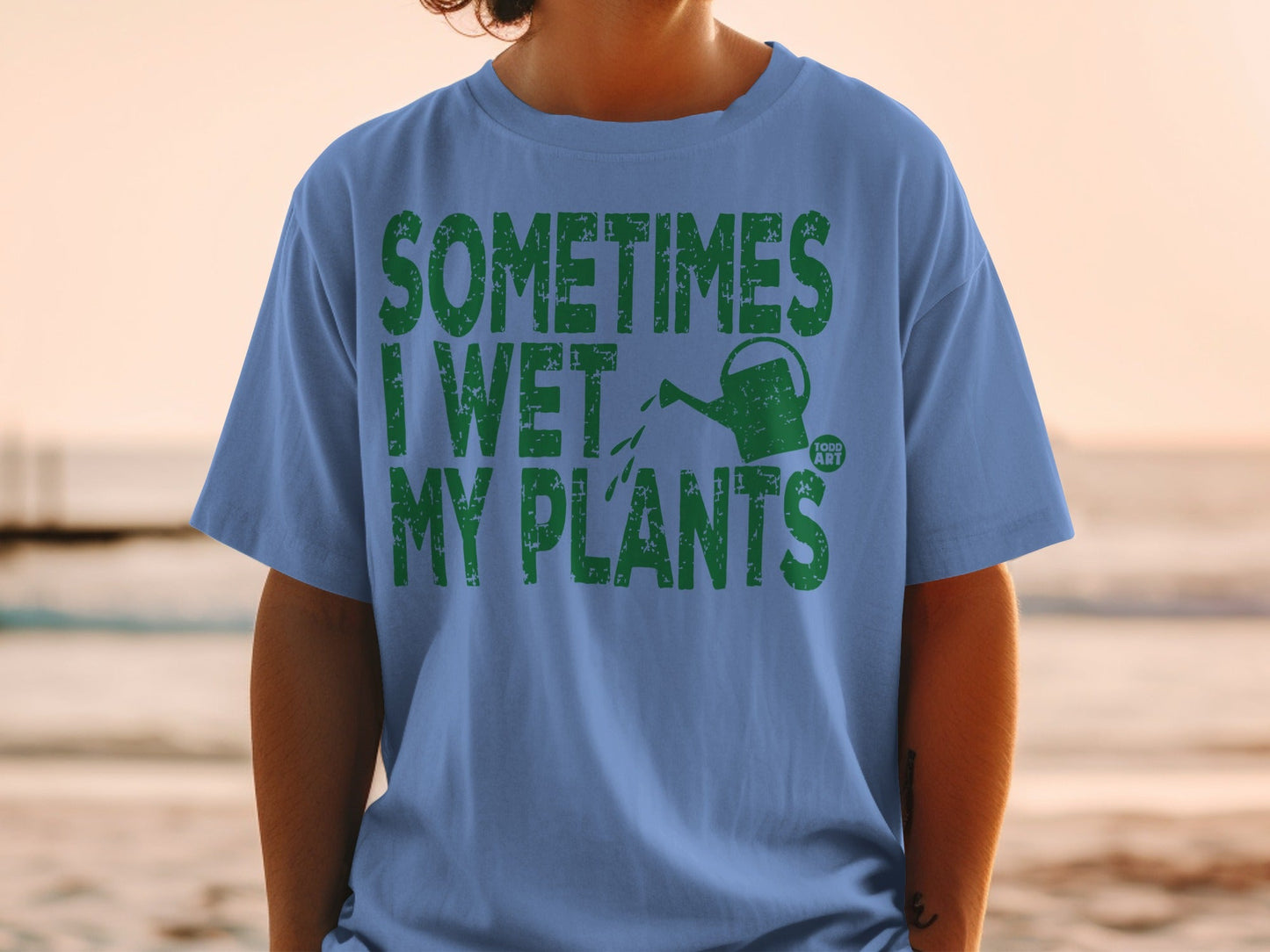 Blue t-shirt with green text "SOMETIMES I WET MY PLANTS" and a watering can.