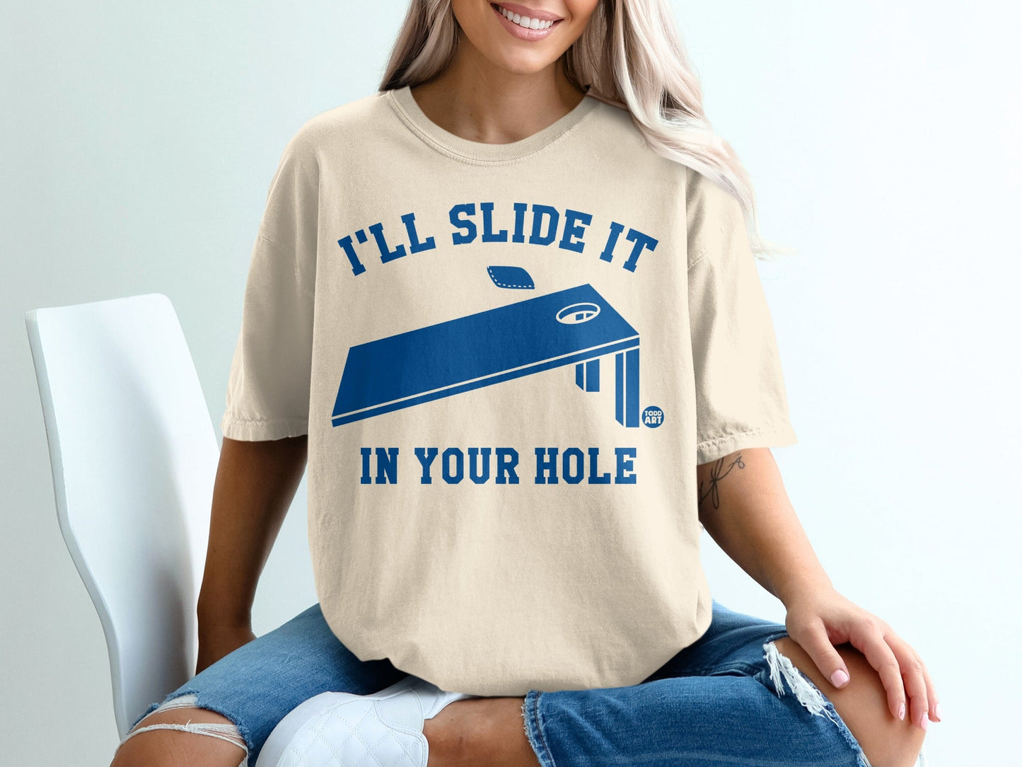 Cream t-shirt with "I'll slide it in your hole" text and cornhole board design.