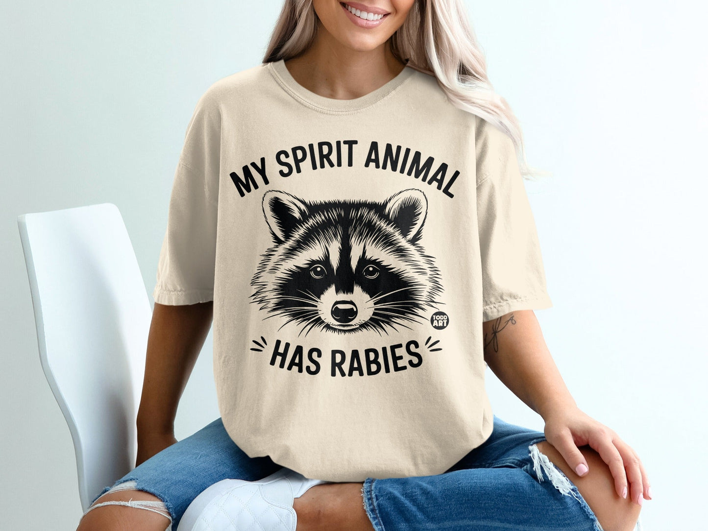 Cream t-shirt with black raccoon graphic and "My spirit animal has rabies" text.