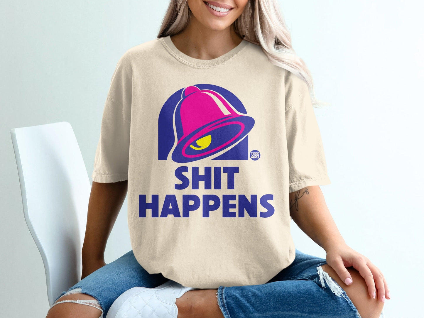 Cream t-shirt with Taco Bell bell logo and "SHIT HAPPENS" text.
