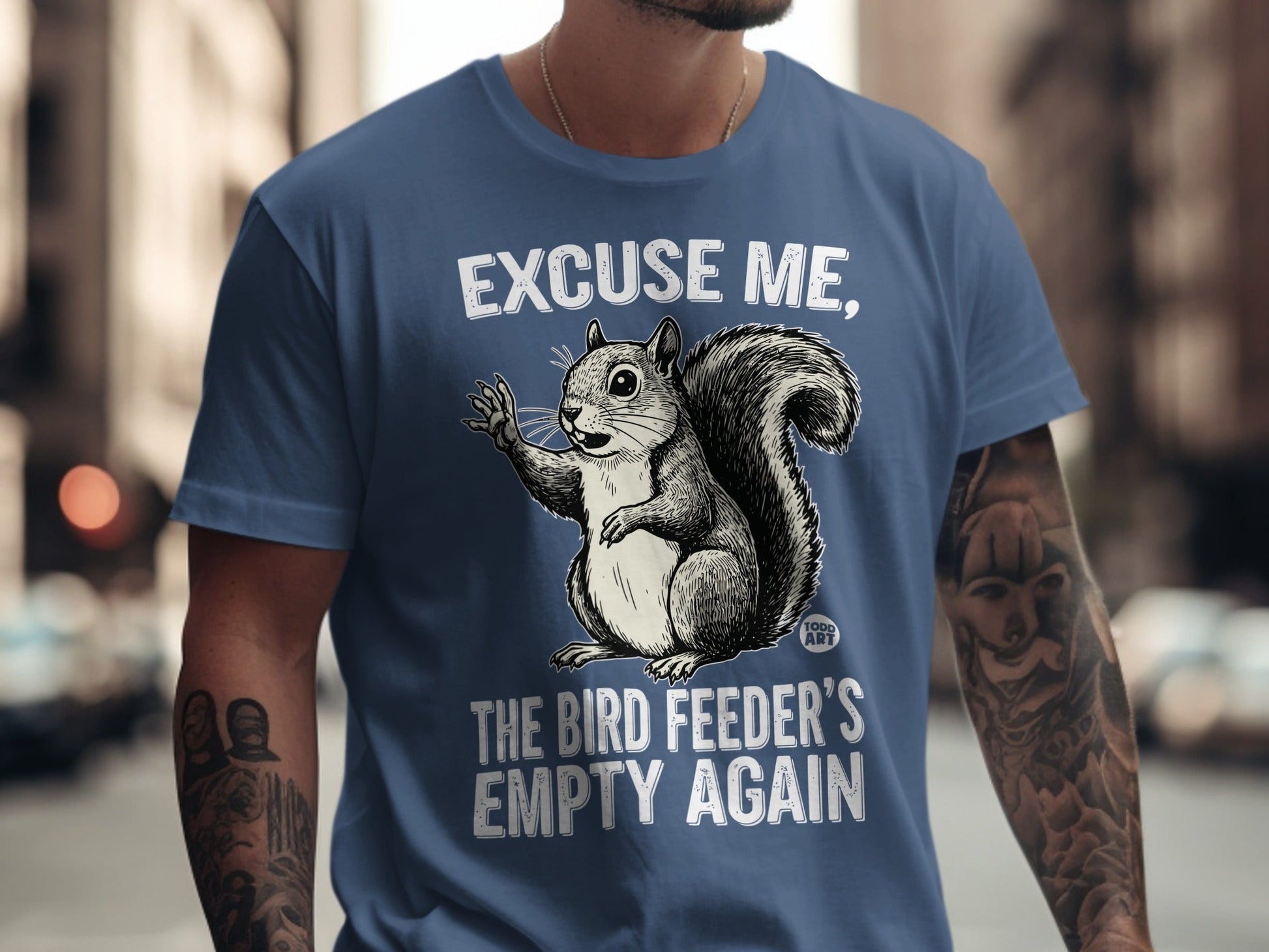 T-shirt with a cartoon squirrel asking "Excuse me, the bird feeder's empty again".