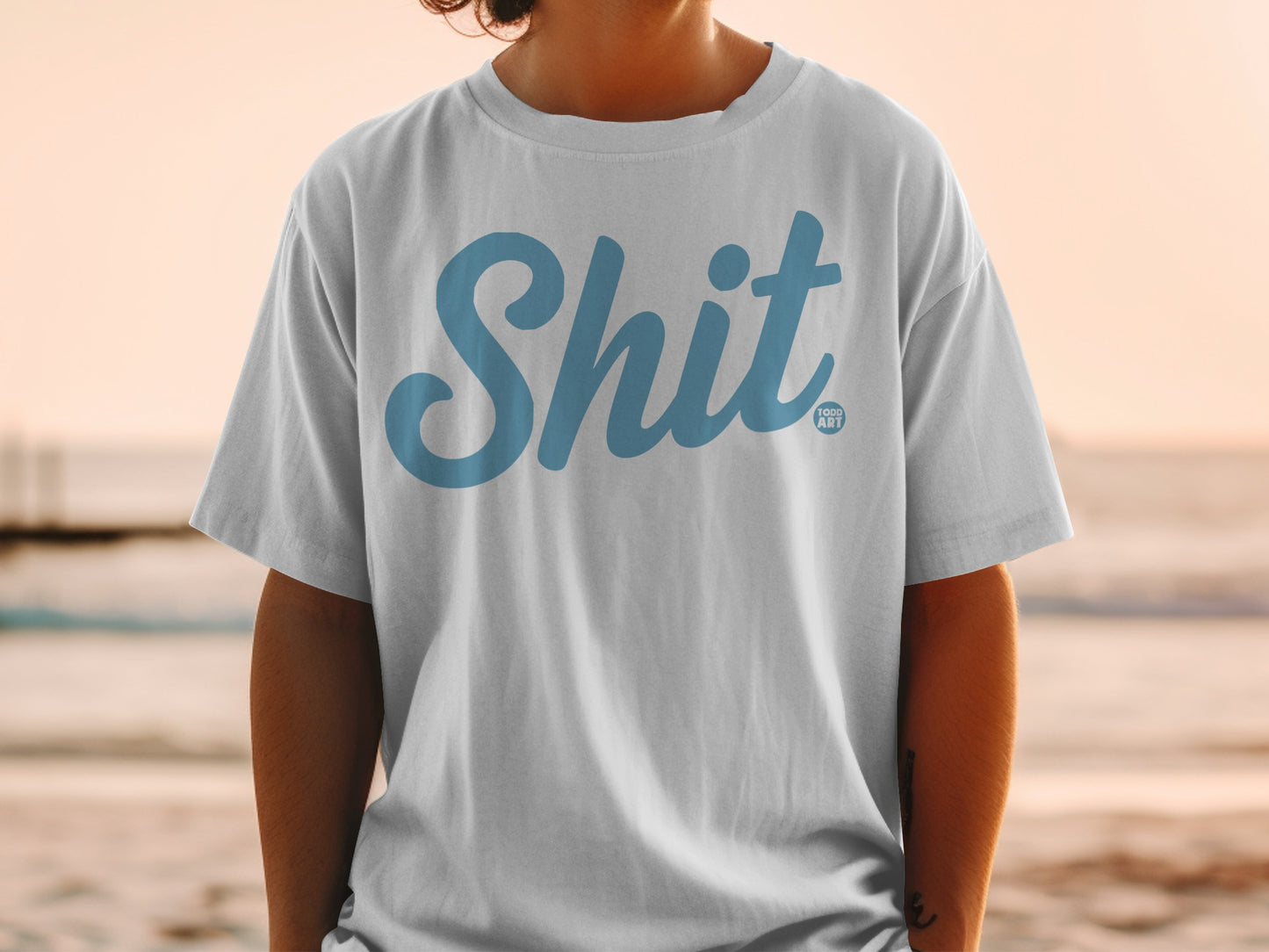 White t-shirt with "Shit" in blue script and "GOOD ART" logo.