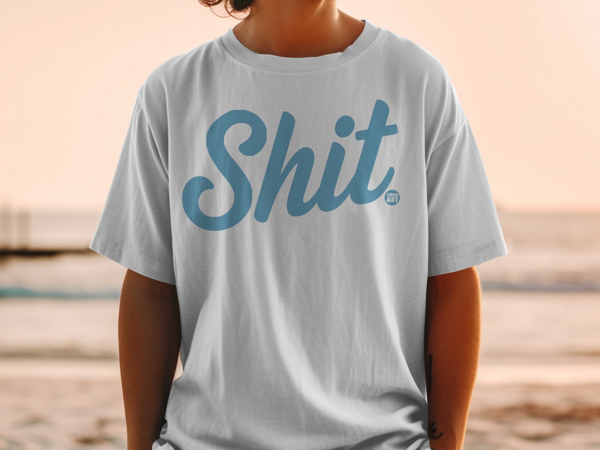 White t-shirt with "Shit" in blue script and "GOOD ART" logo.